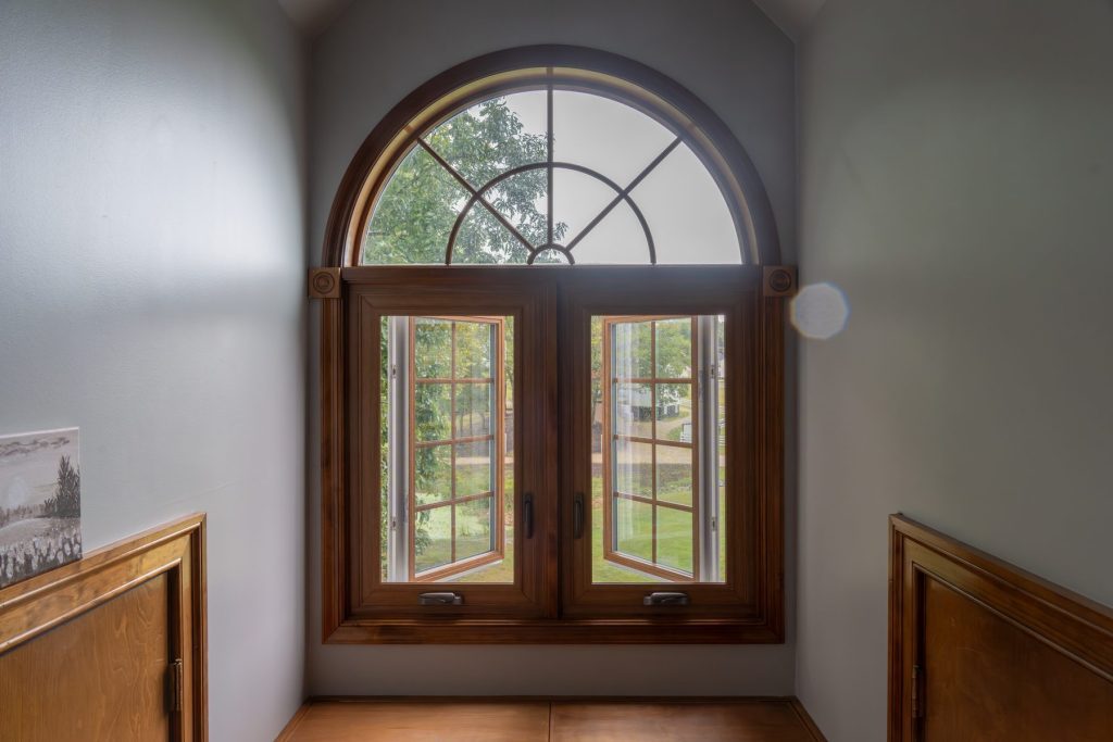 Vytex double casement windows with woodgrain interior and an arched transom