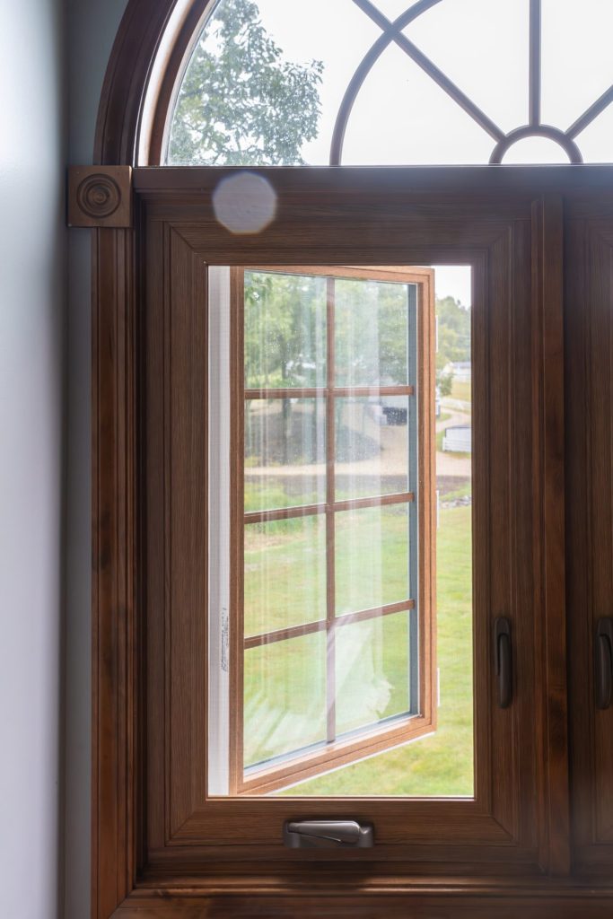 Vytex woodgrain casement window with an arched top and garden view