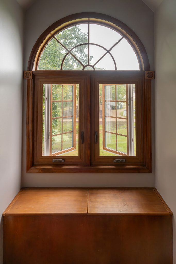 Vytex woodgrain casement windows with an arched top over a window seat