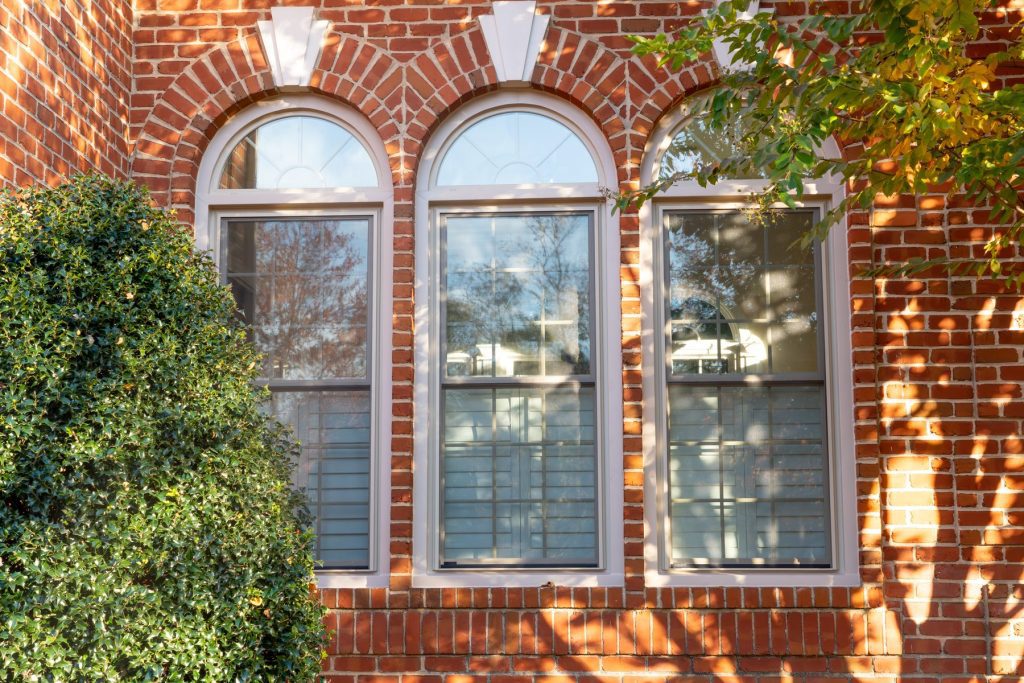 Vytex Fortis windows with arched transoms on a brick home