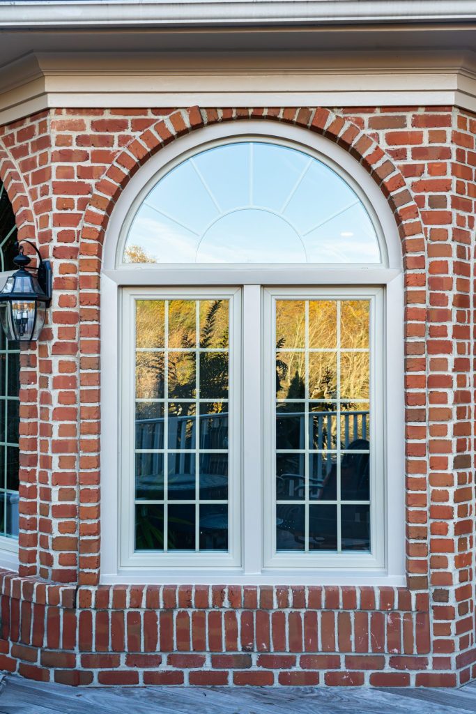 Vytex Fortis arched window with beige frame on brick
