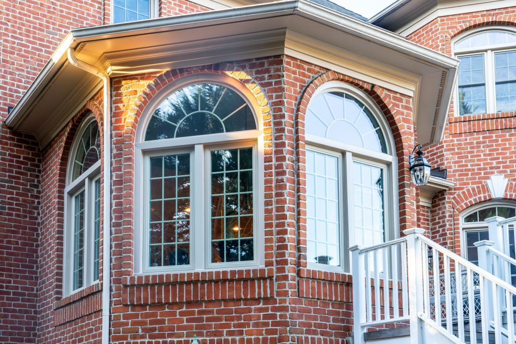 Vytex Fortis bay window with beige frames on a brick home