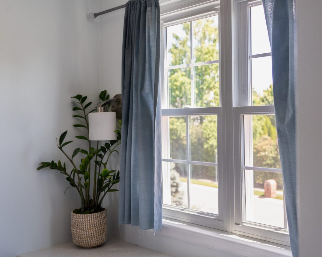 Vytex Fortis white double-hung window with blue curtains