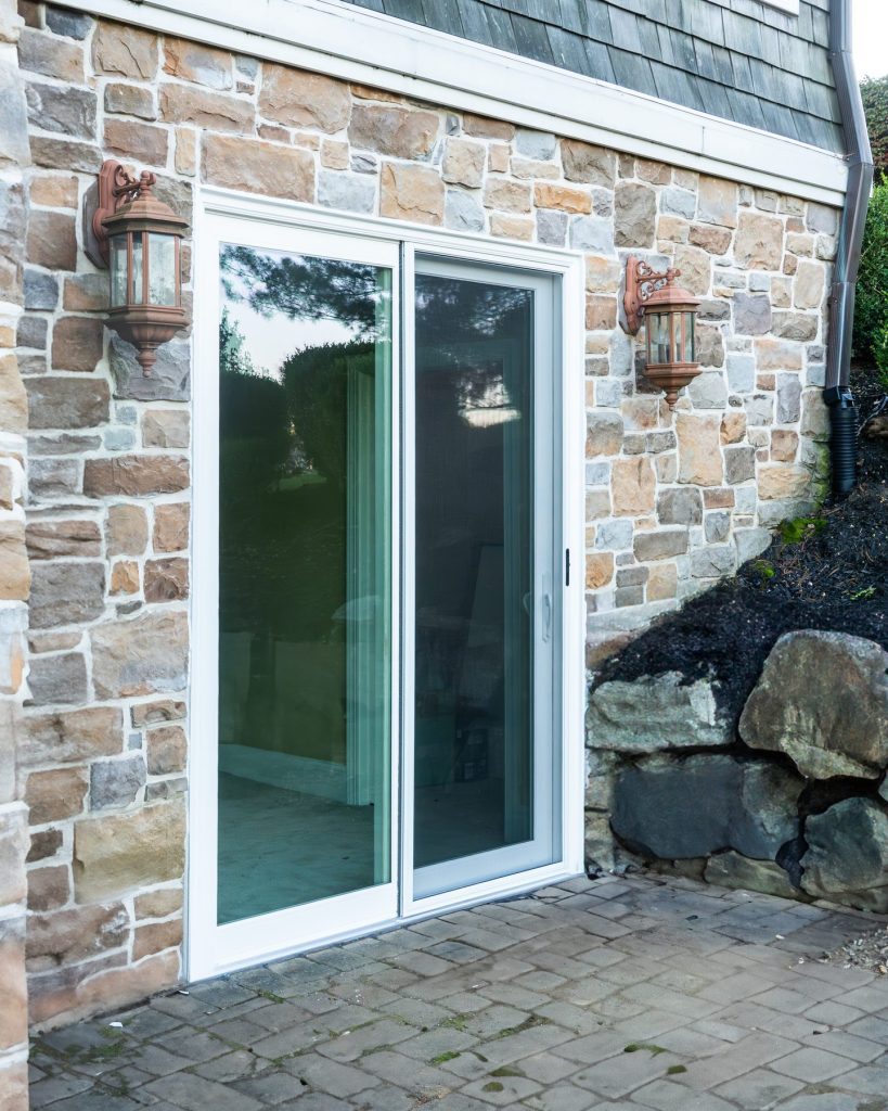 Vytex Signature Series white sliding patio door on a stone wall